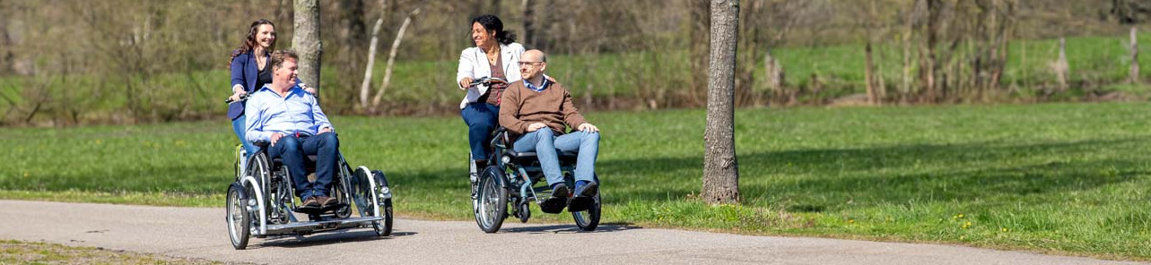 Zwei Männer im Rollstuhl werden im Rollstuhlfahrrad gefahren
